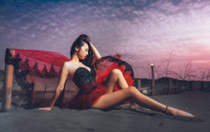 穿紅裙的女性在黃昏時坐在沙灘上