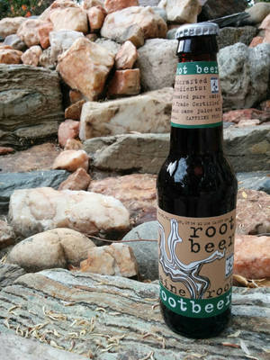一個root beer樽喺石牆前面嘅木頭上休息。 — 石頭 壁紙