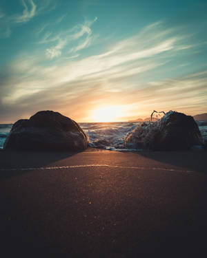 海洋上的夕陽，海浪拍打岩石和沙灘
