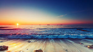 夕陽下的海洋，海浪拍打沙灘，遠處船隻