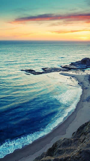海洋上的夕陽，海浪拍打懸崖旁的沙灘 — 海灘日落 壁紙