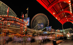 夜間遊樂園，有摩天輪和紅色天篷，在燈串下。