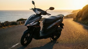 黑色滑板車在金色日落時停在海邊道路上。