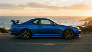 藍色日產Skyline GT-R停泊在日落時分的海岸公路上，俯瞰海洋懸崖