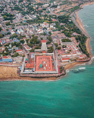 俯瞰海岸寺廟建築群，紅色屋頂與碧綠海水。