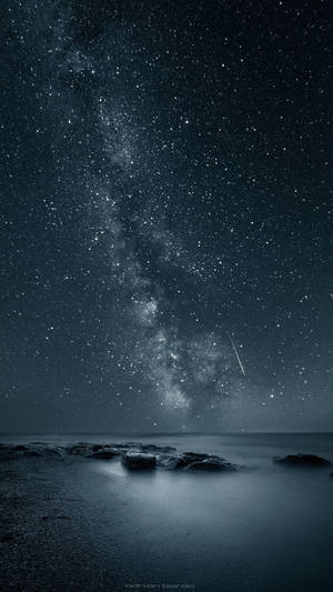 在繁星點點的夜空下，銀河系位於黑暗的海洋岩石之上 — 夜空 壁紙