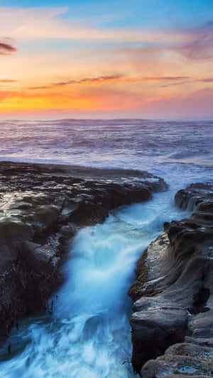 海浪在夕陽下衝過黑暗的岩石，天空呈現火熱的橙色