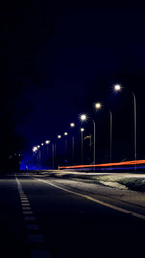夜晚街道，有發光的街燈和模糊的車燈掠過。