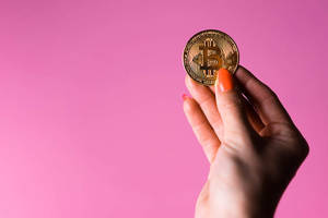 手在粉紅色背景上拿著金色比特幣硬幣 — 粉彩粉紅色 壁紙