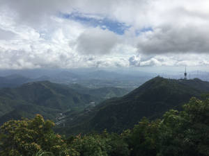 山脊，遠處可見城市天際線，在多雲的天空下。 — 唐人街 GIF 壁紙