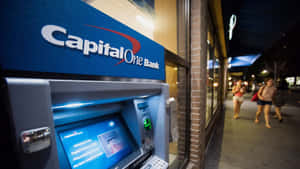 夜晚城市行人路上嘅 Capital One 自動櫃員機，有行人行過。