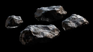 四顆漂浮的小行星，表面粗糙，背景為黑色太空。
