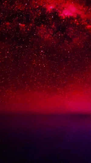 在黑暗地平線上方，紅色和紫色的宇宙天空，點綴著星星和星雲。 — 紅色美學 壁紙