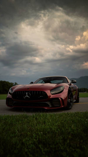 紅色 Mercedes-AMG GT 跑車停泊在路邊，天空風起雲湧。