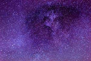 夜空中廣闊的紫色和藍色星場，帶有發光的宇宙塵埃雲。