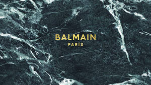 金色 Balmain Paris 標誌在深色大理石背景上