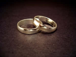 兩枚銀色結婚戒指在深色紋理表面上交織。