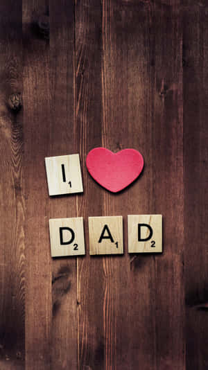 Scrabble 字母和心形在木質表面上拼出 I Love Dad。 — iPhone 8 壁紙