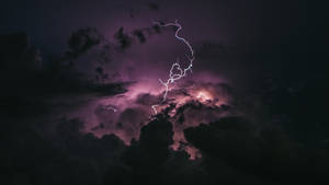一道強烈的閃電照亮了暴風雨的紫色夜空。
