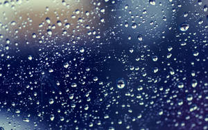 窗戶上的雨滴，背景模糊的藍色和黃色。
