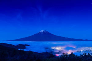 夜空下的富士山，雲層和城市燈光在繁星點點的天空下
