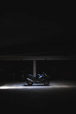 一輛電單車在黑暗的停車場中被聚光燈照亮。