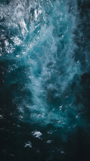 從上方看到的，在深藍色海水中撞擊的帶有白色泡沫的洶湧海浪。