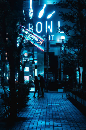 剪影情侶在夜晚的城市人行道上走在霓虹燈招牌下。 — 夜景城市 壁紙