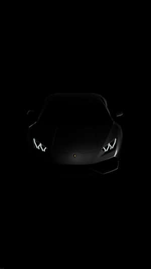 在完全黑暗中車頭燈發光的黑色林寶堅尼。