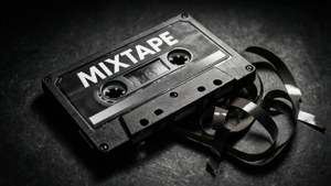 一盒標有 mixtape 的黑色卡式錄音帶，磁帶在深色表面上展開。