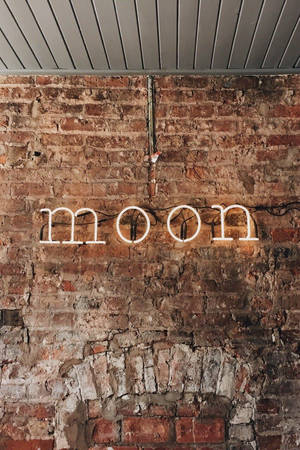喺質樸磚牆上寫住moon嘅霓虹燈牌。