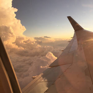 金色日落中蓬鬆雲朵上的飛機翼