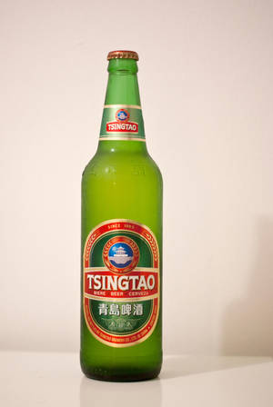 白色表面上的綠色青島啤酒瓶