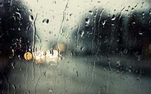 汽車窗戶上的雨滴，背景是模糊發光的路燈。