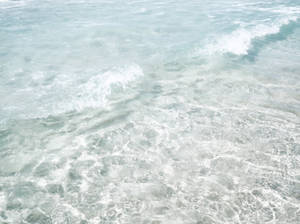 清澈藍綠色海水中翻滾著白色泡沫的溫柔海浪。