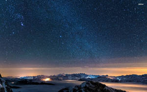 在繁星點點的夜空下，積雪的山峰和下方閃爍的極光雲。 — 晴朗天空 壁紙