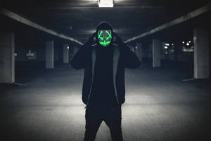 在黑暗停車場中戴著發光綠色骷髏面具和耳機的人。 — 淨化面具 壁紙