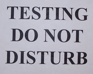 一個標誌，淺灰色紙張上以粗體黑色文字寫著 testing do not disturb。
