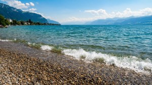 海浪湧上卵石海灘，背景有山和藍天。