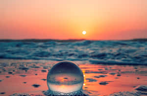 沙灘上的玻璃球反射海洋波浪上的日落 — 湖 壁紙