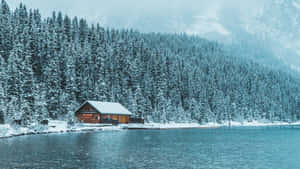 白雪覆蓋的小屋，位於寧靜的湖邊，被松樹和山巒環繞。