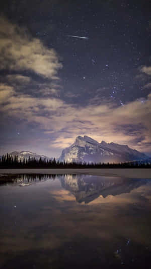 夜晚平靜的湖面倒映著雪山和星空。