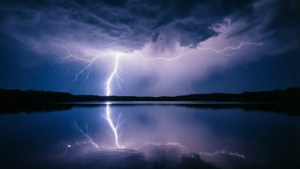 一道強烈的閃電照亮了暴風雨的夜空，倒映在平靜的湖面上，岸邊有黑暗的樹木。