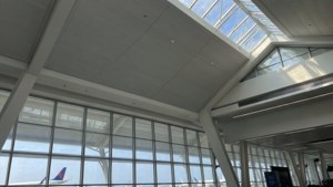 高天花、大窗戶、可見飛機尾翼的機場客運大樓。