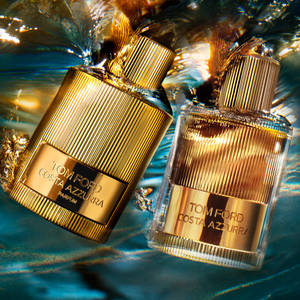兩支金色Tom Ford香水瓶在水中，帶有光線反射。