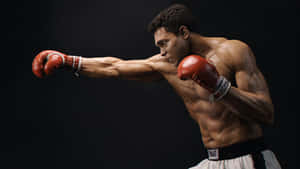 一位戴紅色手套的拳擊手在黑暗中揮拳，汗水飛濺。 — 拳擊 壁紙