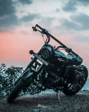 日落時分，黑色 Royal Enfield 電單車停泊喺山丘上。