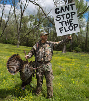 獵人抱著火雞和寫著「CANT STOP THE FLOP」的標牌，身處草地田野。