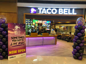 Taco Bell餐廳入口，設有紫色和黑色氣球柱及現已開業標誌。