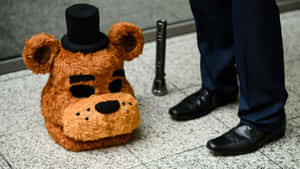Freddy Fazbear頭戴高帽在瓷磚地上，旁邊有人的腿和護柱。